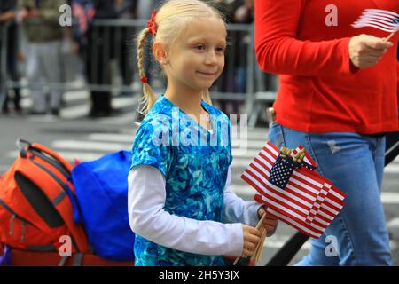 New York, N.Y/USA – 11. November 2021: Ein Kind schwingt während der Veterans Day Parade auf der Fifth Avenue in New York am 11. November 2021 die Flagge der Vereinigten Staaten. Quelle: Gordon Donovan/Alamy Live News) Stockfoto
