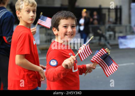 New York, N.Y/USA – 11. November 2021: Ein Kind schwingt während der Veterans Day Parade auf der Fifth Avenue in New York am 11. November 2021 die Flagge der Vereinigten Staaten. Quelle: Gordon Donovan/Alamy Live News) Stockfoto