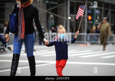 New York, N.Y/USA – 11. November 2021: Ein Kind schwingt während der Veterans Day Parade auf der Fifth Avenue in New York am 11. November 2021 die Flagge der Vereinigten Staaten. Quelle: Gordon Donovan/Alamy Live News) Stockfoto