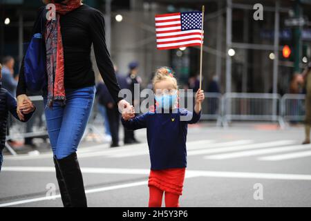 New York, N.Y/USA – 11. November 2021: Ein Kind schwingt während der Veterans Day Parade auf der Fifth Avenue in New York am 11. November 2021 die Flagge der Vereinigten Staaten. Quelle: Gordon Donovan/Alamy Live News) Stockfoto