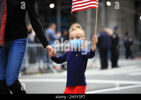 New York, N.Y/USA – 11. November 2021: Ein Kind schwingt während der Veterans Day Parade auf der Fifth Avenue in New York am 11. November 2021 die Flagge der Vereinigten Staaten. Quelle: Gordon Donovan/Alamy Live News) Stockfoto