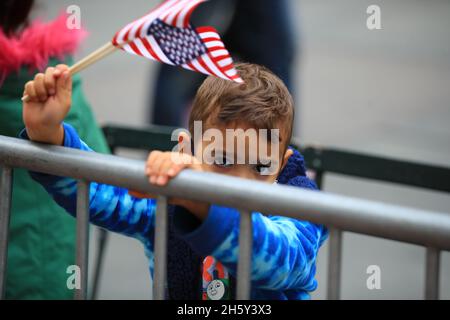 New York, N.Y/USA – 11. November 2021: Ein Kind schwingt während der Veterans Day Parade auf der Fifth Avenue in New York am 11. November 2021 die Flagge der Vereinigten Staaten. Quelle: Gordon Donovan/Alamy Live News) Stockfoto