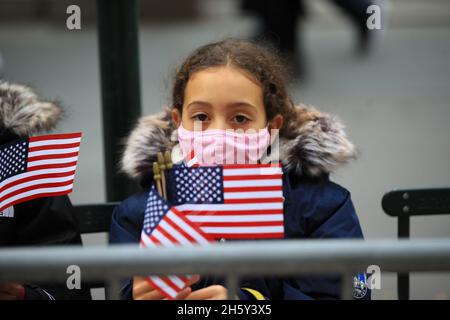 New York, N.Y/USA – 11. November 2021: Ein Kind schwingt während der Veterans Day Parade auf der Fifth Avenue in New York am 11. November 2021 die Flagge der Vereinigten Staaten. Quelle: Gordon Donovan/Alamy Live News) Stockfoto