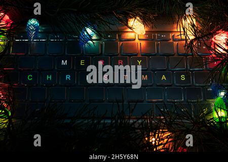 Computertastatur, Schlüssel mit weihnachtsbaum, Nahaufnahme. frohe Weihnachten die Inschrift auf der Laptop-Tastatur im dunklen Licht der Nacht. Stockfoto