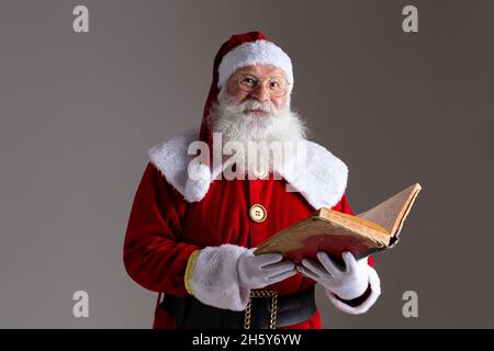 Weihnachtsmann mit einem alten roten Buchumschlag. Das Versetzen von Namen nennt Geschenke für Weihnachten. Weihnachten steht bevor Stockfoto