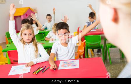 Schüler heben ihre Hände im Klassenzimmer Stockfoto