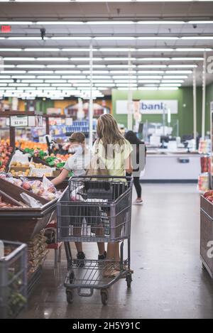 Chicago, IL- 21. August 2021:Mutter und Kind tragen Masken Einkaufen im Supermarkt nur für redaktionelle Zwecke Familie trägt Masken beim Pflücken von Früchten im Supe Stockfoto