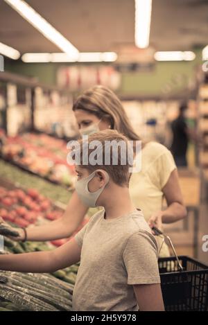 Chicago, IL- 21. August 2021:Mutter und Kind tragen Masken Einkaufen im Supermarkt nur für redaktionelle Zwecke Familie trägt Masken beim Pflücken von Früchten im Supe Stockfoto
