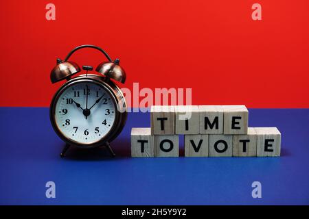 Zeit zum Abstimmen Alphabet Buchstaben mit Wecker auf blauem und rotem Hintergrund Stockfoto