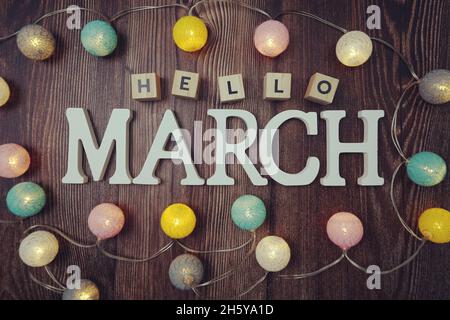 Hello March Alphabet Buchstaben mit LED-Baumwollkugeln Dekoration auf Holzhintergrund Stockfoto