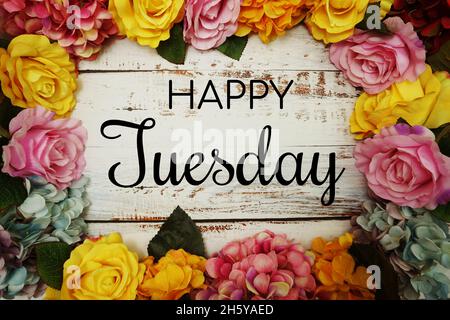 Happy Tuesday Text und Blumen Bunte Grenze Rahmen auf Holzhintergrund Stockfoto