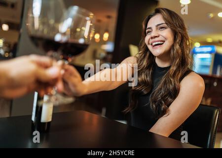Schönes lateinisches junges Paar mit Gläsern Rotwein im Restaurant Stockfoto