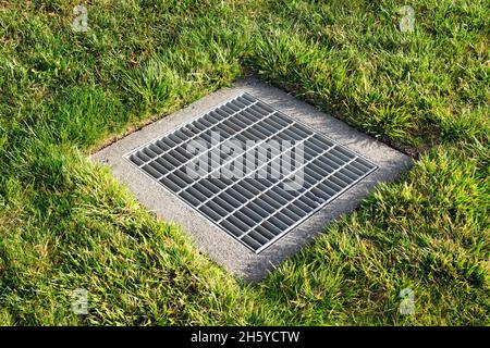 Auffangbecken quadratische Drainage Rost über Sturmwasserablauf von grünem Gras umgeben. Stockfoto