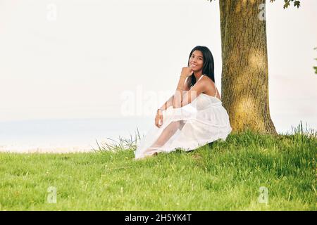 Trost in der Umarmung der Natur finden: Eine Latina-Frau sonnt sich in der friedlichen Umgebung des Sees Stockfoto