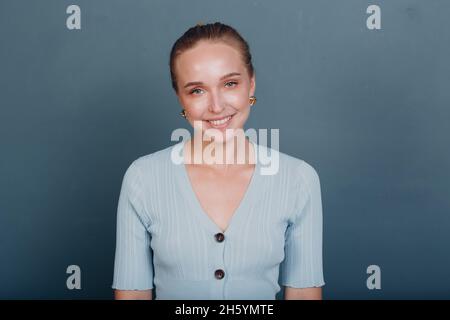 Porträt einer jungen, 20-25 Jahre lächelnden europäischen Frau. Schönes glückliches blondes Mädchen trägt T-Shirt und schaut in die Kamera. Studioaufnahmen auf blauem Hintergrund isoliert. Stockfoto