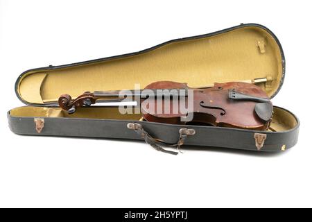 Breites Nahaufnahme-Studio-Aufnahme einer alten, gebrochenen, staubbedeckten Geige mit ihrem alten, zerkratzten Gehäuse, isoliert auf weißem Hintergrund. Vintage beschädigtes Musical Stockfoto