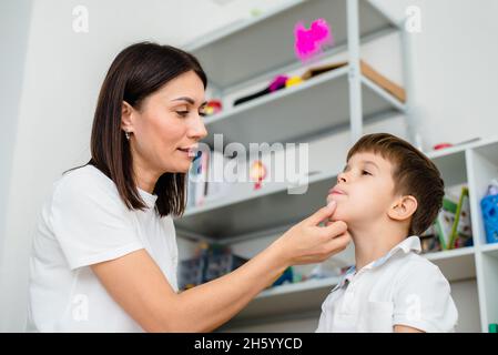 Frau Logopädin Ausbildung Junge richtig blasen mit farbigen Federn Übung Stockfoto