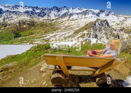 Frau Tourist Entspannung auf einer Bergbank des Aroser Weisshorn Gipfel, Ferienort in der Schweiz. Seilbahnstation der Plessur Alpen in Graubünden Stockfoto