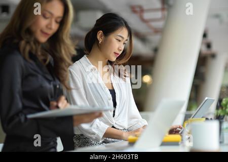 Unternehmerinnen, die an ihrem Laptop arbeiten, arbeiten an einem Projekt für Geschäftsstrategien zusammen. Stockfoto