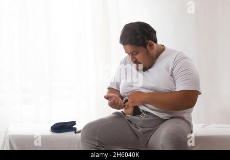 Ein Fettfan, der versucht, Übergewicht mit einer Spritze zu behandeln, indem er sich selbst eine Insulininspritze verabreicht. Stockfoto