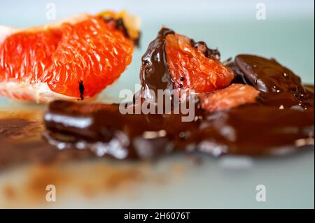 Gelöste Bitterschokolade mit Stücken süßer roter Grapefruit, Nahaufnahme. Stockfoto