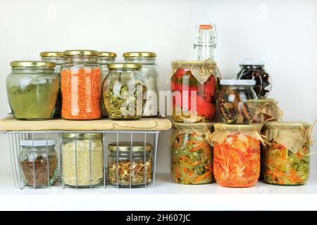 Vielfalt an vegetarischen Produkten und fermentierten Lebensmitteln in Gläsern zur Lagerung auf weißem Holztisch. Gesundes veganes Kochen, sauberes Essen, keine CO-Abfälle Stockfoto