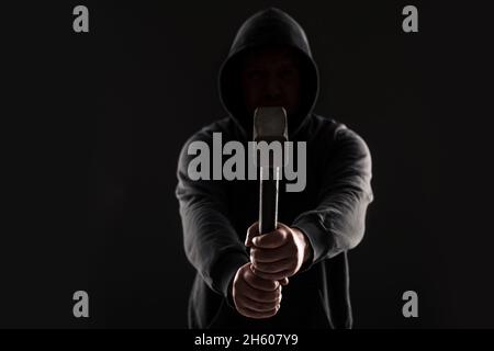 Verbrecher in dunkler Kleidung und Balaclava mit Hammer Stockfoto