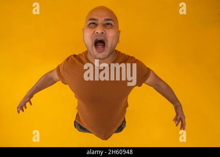 Porträt eines kahlen Mannes, der vor schlichtem Hintergrund steht und schreit. Stockfoto