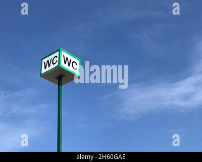 WC-Logo, Zeichen der öffentlichen Toiletten auf der Straße auf Himmel Hintergrund. Stockfoto