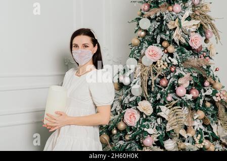 Junge schöne europäische Frau in einer medizinischen Maske mit Urlaub Geschenke zu Hause, Quarantäne Coronavirus. Stockfoto