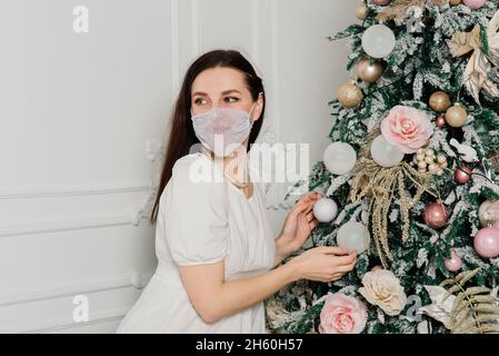 Junge schöne europäische Frau in einer medizinischen Maske mit Urlaub Geschenke zu Hause, Quarantäne Coronavirus. Stockfoto