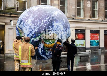 Glasgow, Großbritannien. November 2021. Aktivisten tragen einen Globus nach einem Protest von Oxfam. Zwei Wochen lang ringen in Glasgow rund 200 Länder darum, wie das Ziel, die globale Erwärmung im Vergleich zu vorindustriellen Zeiten möglichst auf 1.5 Grad zu begrenzen, noch erreicht werden kann. Quelle: Christoph Soeder/dpa/Alamy Live News Stockfoto