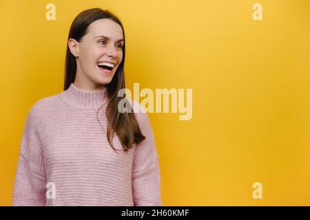 Portrait of Young Surpared Stauned beeindruckt glücklich kaukasische Frau in rosa gestrickten Pullover Blick neben mit Kopierer Platz Stockfoto