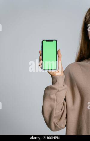 Frau, die das Telefon in der Hand hält, mit grünem Bildschirm Stockfoto