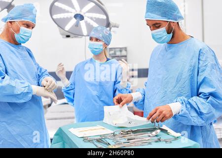 OP-Team in Schutzkleidung mit sterilen chirurgischen Instrumenten vor der Notfalloperation Stockfoto