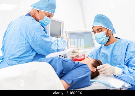 Chirurg und Anästhesist arbeiten zusammen, um den Patienten vor der Operation zu naresisieren Stockfoto