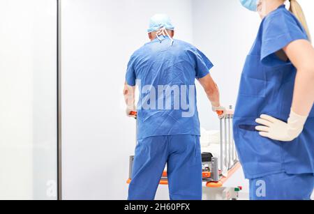 Das Pflegepersonal schiebt das Patientenbett vor der Operation durch den Krankenhausflur Stockfoto