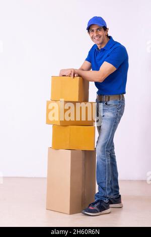 Der Lieferer schaute auf die Kamera, während er mit Pappkartons stand Stockfoto