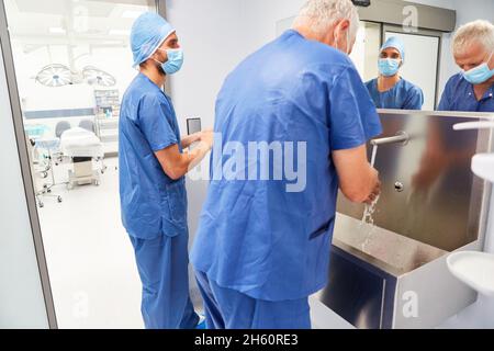 Die Chirurgen waschen ihre Hände zur Desinfektion am Waschbecken vor dem Operationssaal Stockfoto