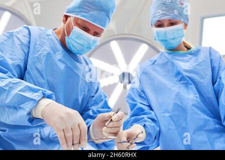 Das medizinische Team arbeitet während eines chirurgischen Eingriffs in der Klinik konzentriert zusammen Stockfoto