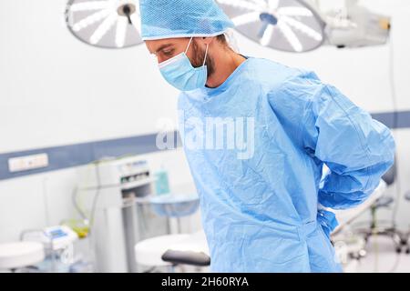 Chirurg trägt eine Gesichtsmaske, während er ein Kleid anlegt, um sich auf die Operation im Operationssaal vorzubereiten Stockfoto