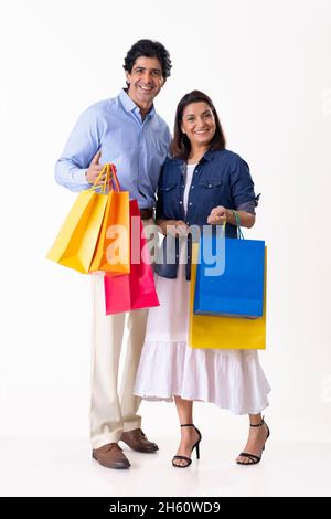 Indisches Ehepaar mittleren Alters, das zusammen mit Einkaufstüten steht Stockfoto