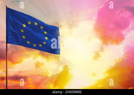 Flatternde Flagge der Europäischen Union in der linken oberen Ecke Mockup mit dem Ort für Ihre Informationen über schöne bunte Sonnenuntergang oder Sonnenaufgang Hintergrund. Stockfoto