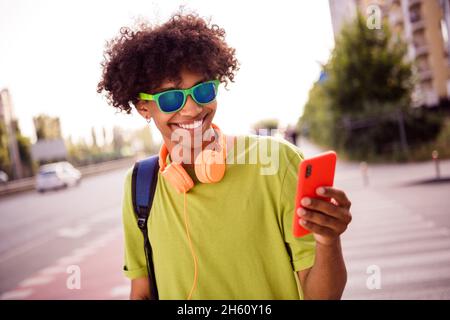 Portrait von attraktiven fröhlichen Kerl mit Gerät Blogging Musik hören genießen verbringen Freizeit sonnigen Tag Wochenende im Freien Stockfoto