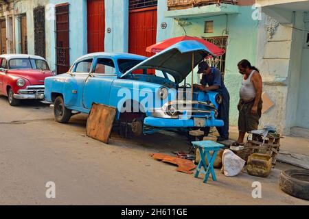 Straßenszene im Zentrum von Havanna. Männer reparieren geparkte „Yank Tank“, La Habana (Havanna), Habana, Kuba Stockfoto