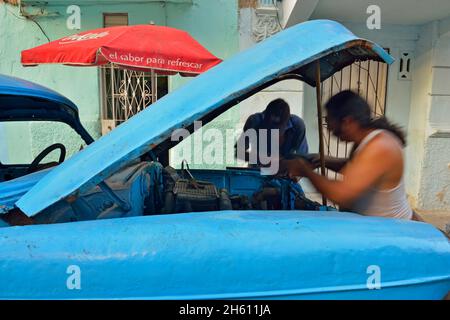 Straßenszene im Zentrum von Havanna. Männer reparieren geparkte „Yank Tank“, La Habana (Havanna), Habana, Kuba Stockfoto