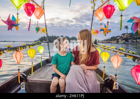 Glückliche Familie Mutter und Sohn von Reisenden reiten auf einem Nationalboot auf dem Hintergrund der alten Stadt Hoi, Vietnam. Vietnam öffnet sich danach wieder für Touristen Stockfoto