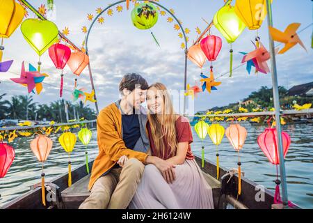 Ein glückliches Paar von Reisenden fährt auf einem Nationalboot auf dem Hintergrund der alten Stadt Hoi in Vietnam. Vietnam öffnet sich nach der Quarantäne wieder für Touristen Stockfoto
