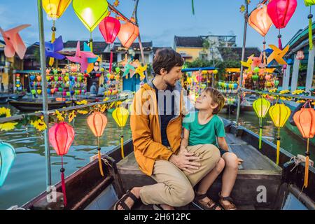 Glückliche Familie Vater und Sohn von Reisenden fahren ein nationales Boot auf dem Hintergrund von Hoi an alten Stadt, Vietnam. Vietnam öffnet sich danach wieder für Touristen Stockfoto
