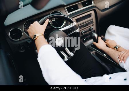 Der Mann in weißem Hemd sitzt in Nahaufnahme hinter dem Steuer eines offenen Autos Stockfoto